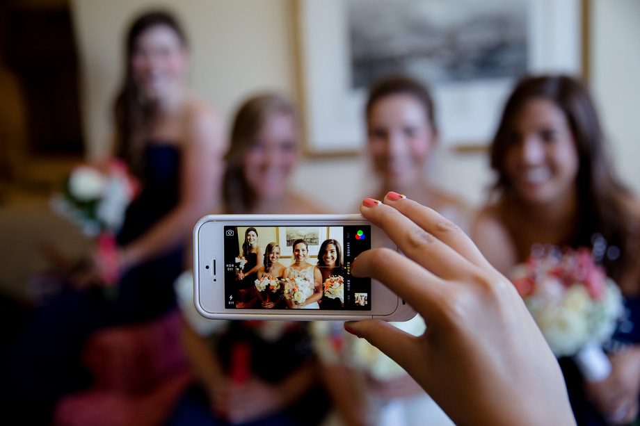 Bridesmaid with pretty fingernails taking an iPhone photo of the girls with the bride