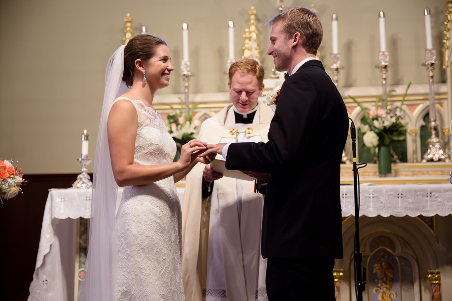 Groom placing wedding ring on brides finger at the conclusion of marriage ceremony