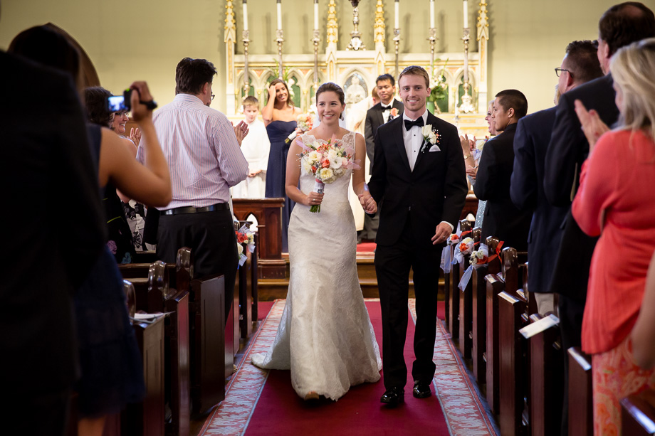 Bride and groom walking down the aisle after marriage ceremony as guests look on