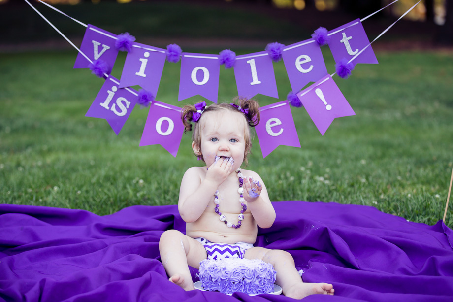 Baby happily eating handfuls of birthday cake