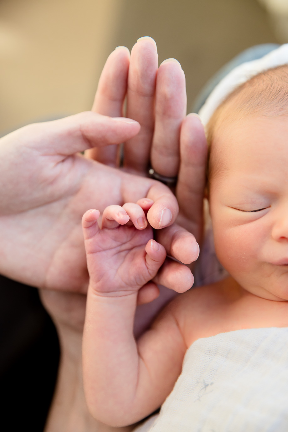 mother and father holding hands with tiny little newborn baby