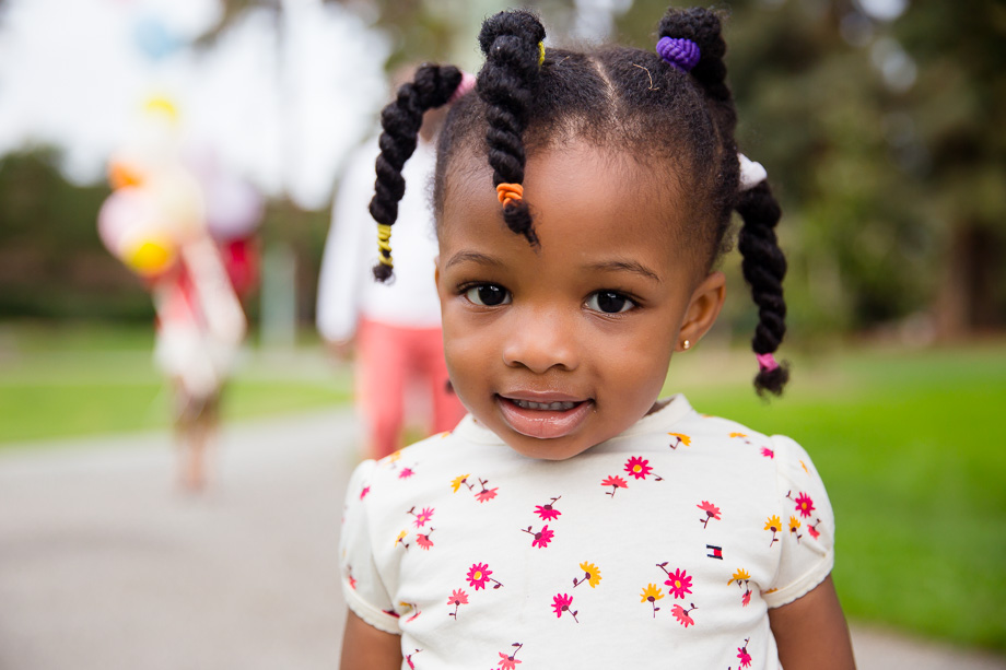 shot of little girl in the park with her parents behind her