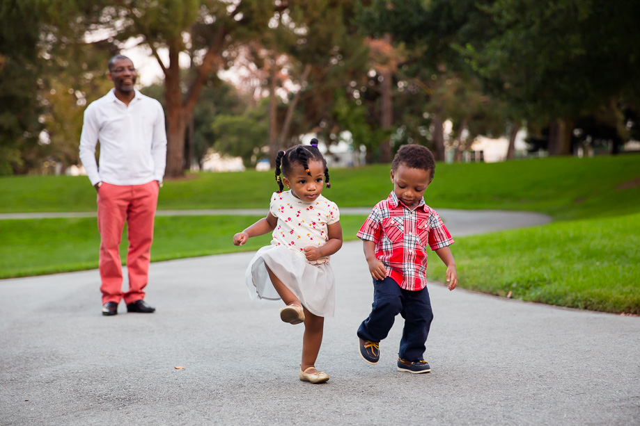 kids walking/dancing in the park with dad watching from behind them