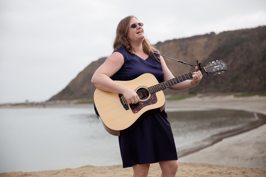 Bride and grooms friend playing guitar and singing at their ceremony