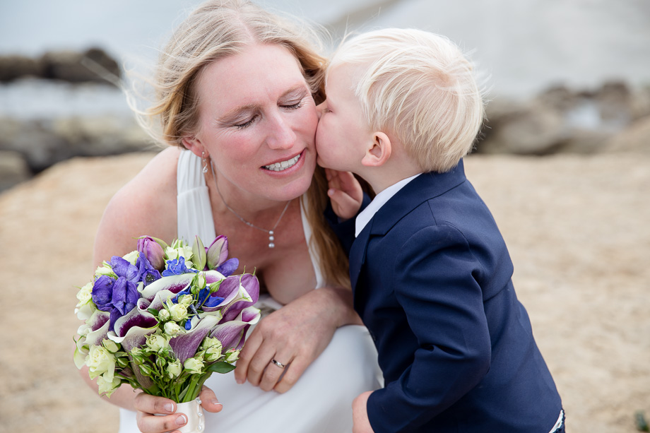 Adorable little ring bearer kissing the bride on her cheek
