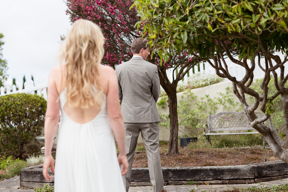 Groom peeking back over his shoulder for the cute first look