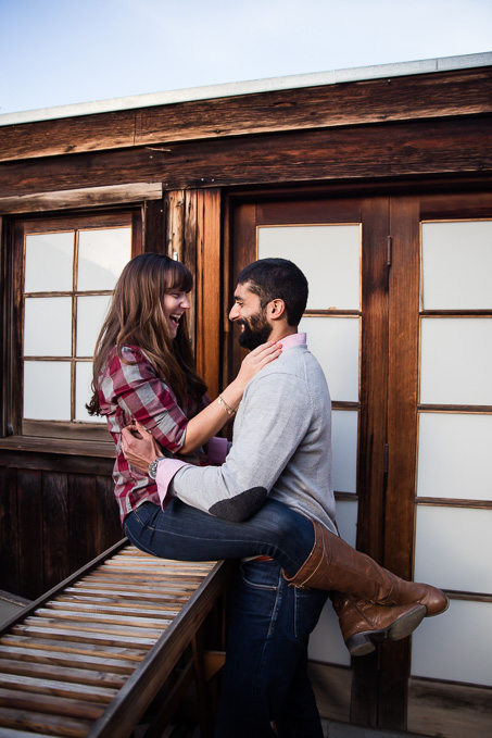 wife sitting on wooden railing looking at husband