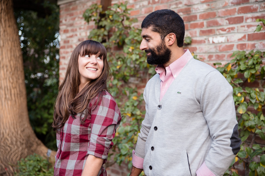 couple looking at each other in front of red brick wall covered in vines at Elizabeth F Gamble Garden