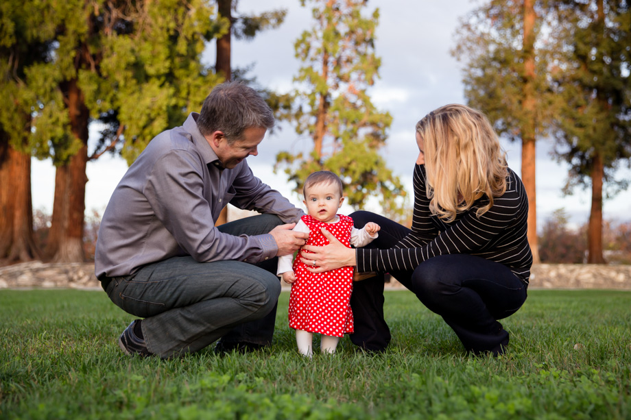 Nine-month-old baby is trying to walk on her tiny feet, with parents help