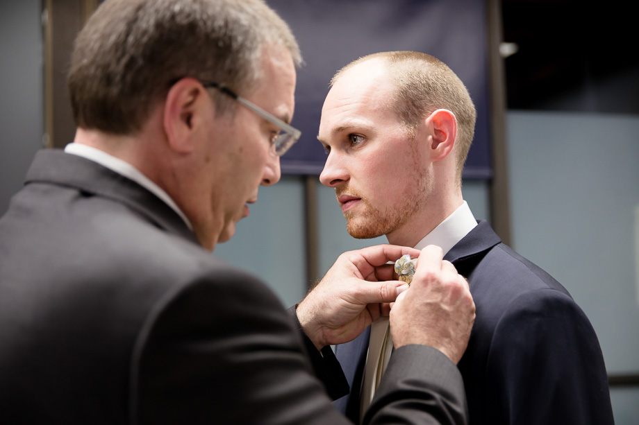 Grooms dad is helping him to pin the boutonniere on