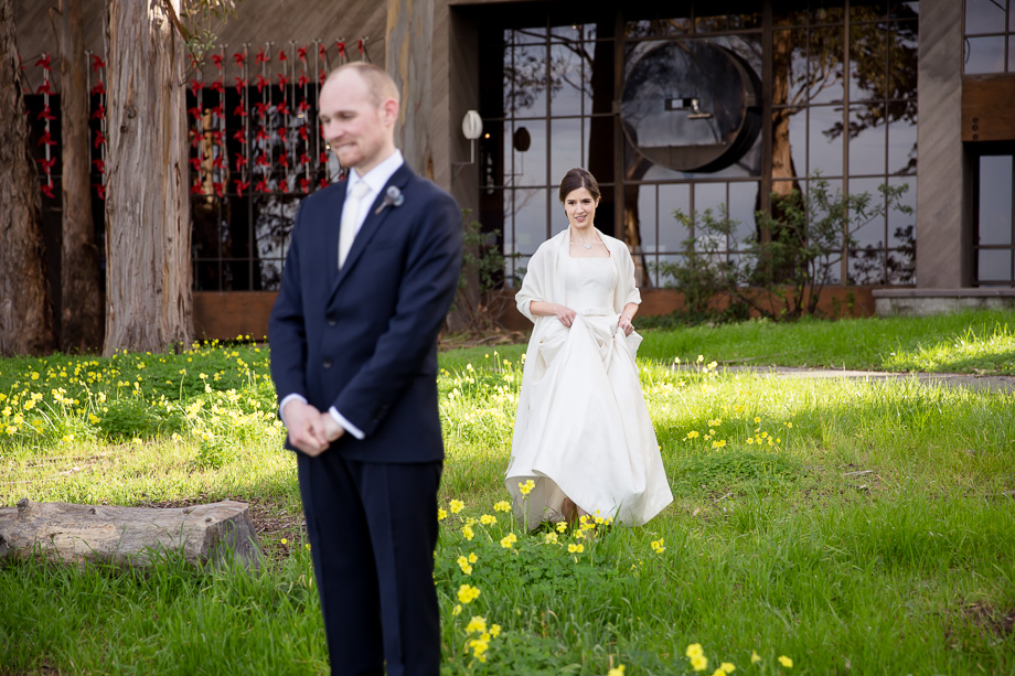bride approaching the groom from behind outside CuriOdyssy