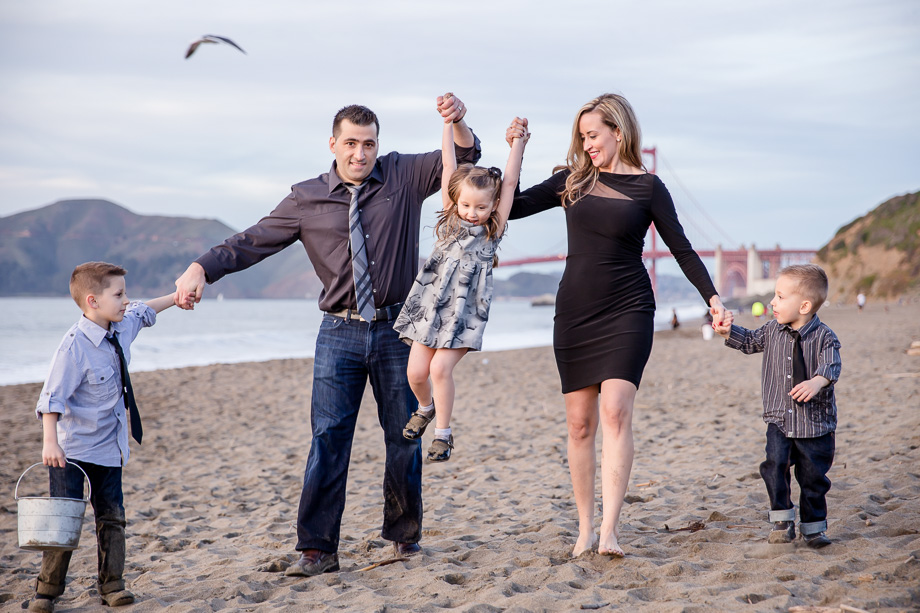 parents lifting baby girl up on the beach - a beautiful family of five