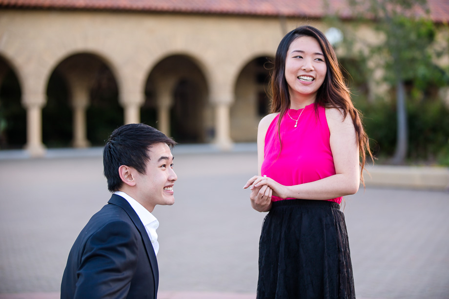 happy couple smiling at everyone around them cheering and clapping as she said yes