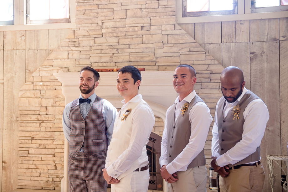 groom watches his bride walking down the aisle