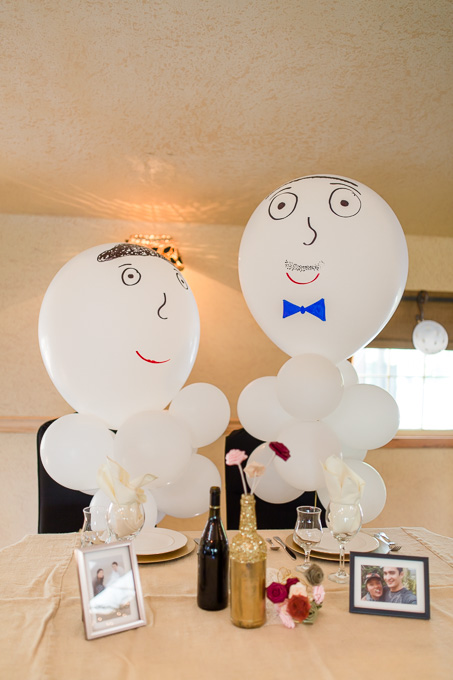 friends surprised bride and groom with two giant balloons with faces at their sweetheart table