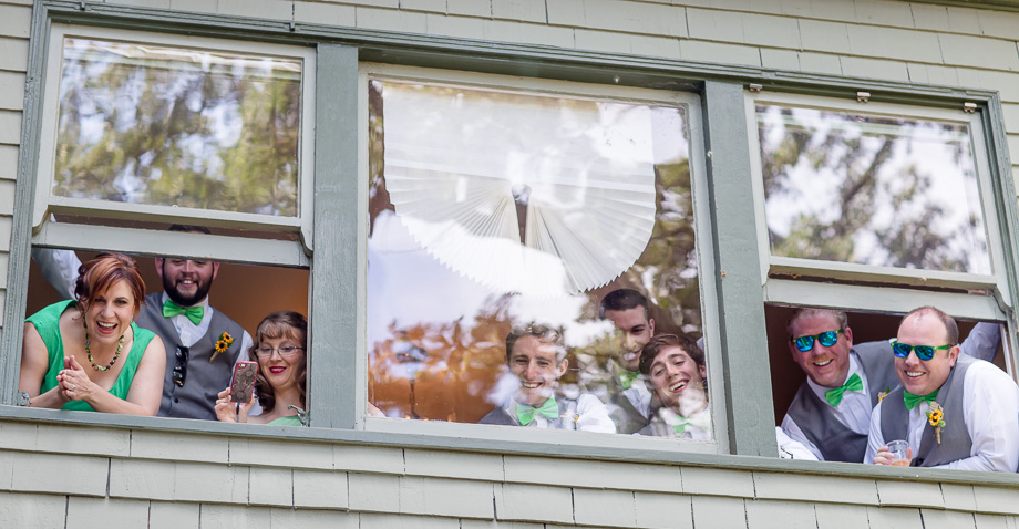 bridesmaids and groomsmen peeking out of the window for the first look