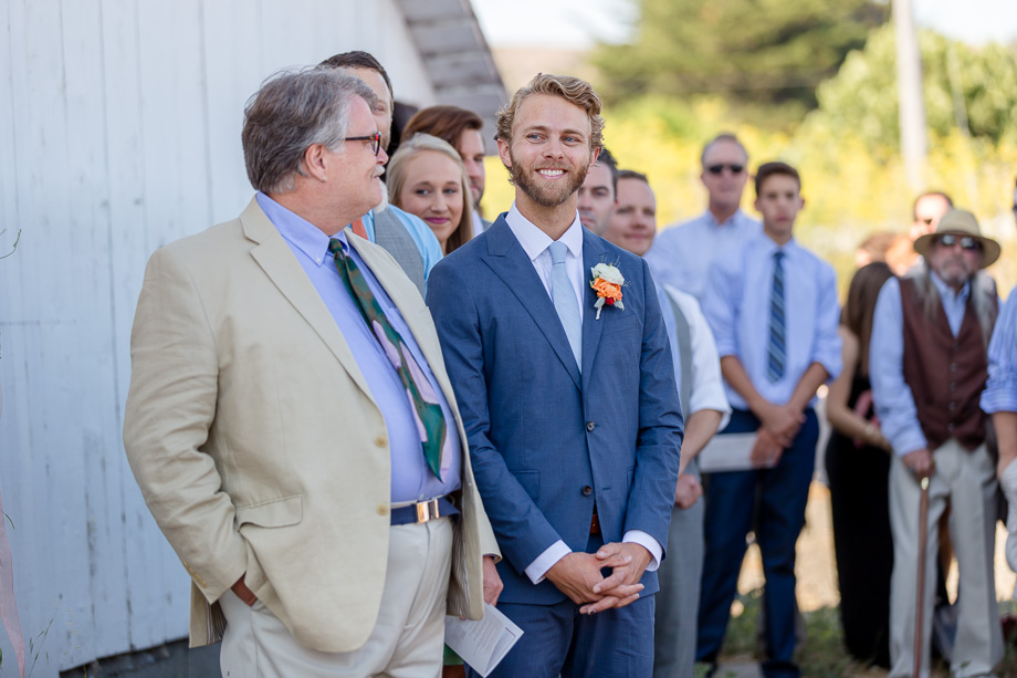 groom getting emotional watching his bride walking down the path