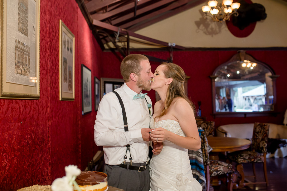 bride and groom messy kiss after cutting wedding cake