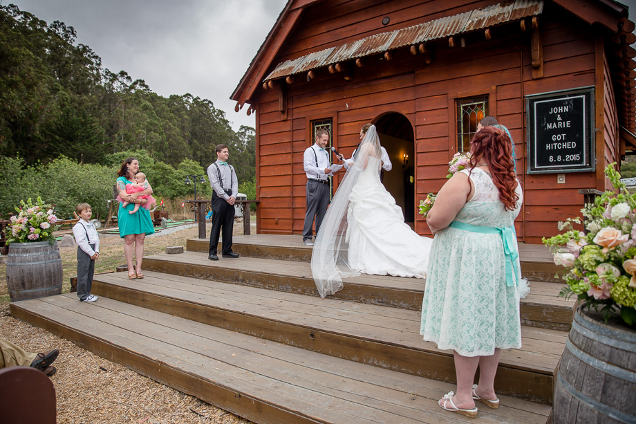 couple exchanging vows in front of the red chapel