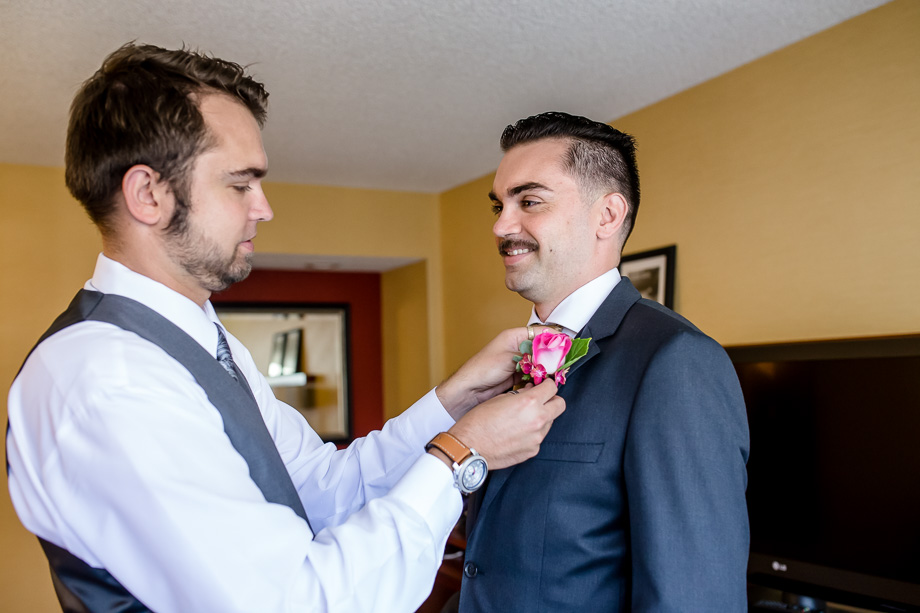 groomsman pinning boutonniere on groom