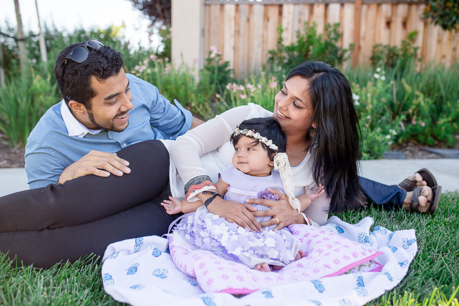 outdoor family photo of baby girl and parents in grass