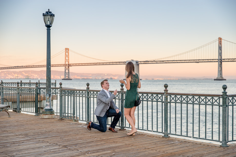 a romantic sunset suprise proposal in San Francisco in front of the Bay Bridge