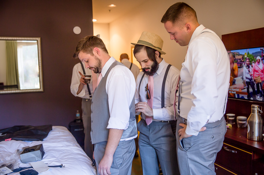 helping groom put on vest