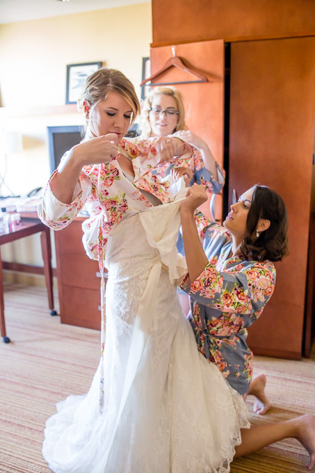 bridesmaids helping bride put on her gown