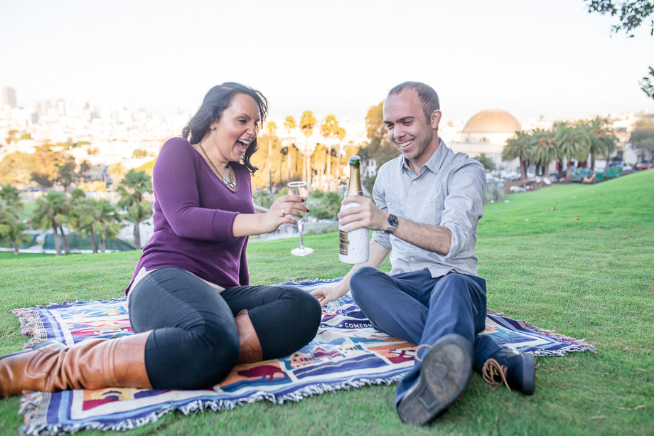 popping open champagne during engagement photo shoot