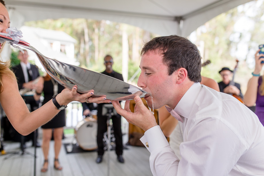 groom drinking champagne out of a giant spoon