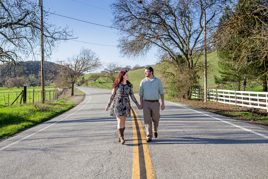 couple holding hands walking along a country highway