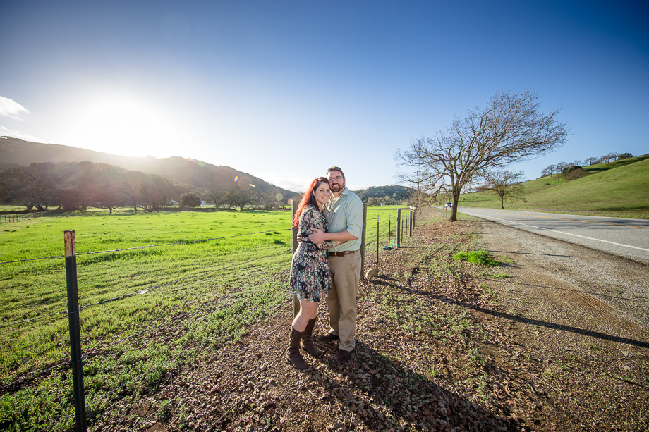 engagement photo at a field under bright sunny sky