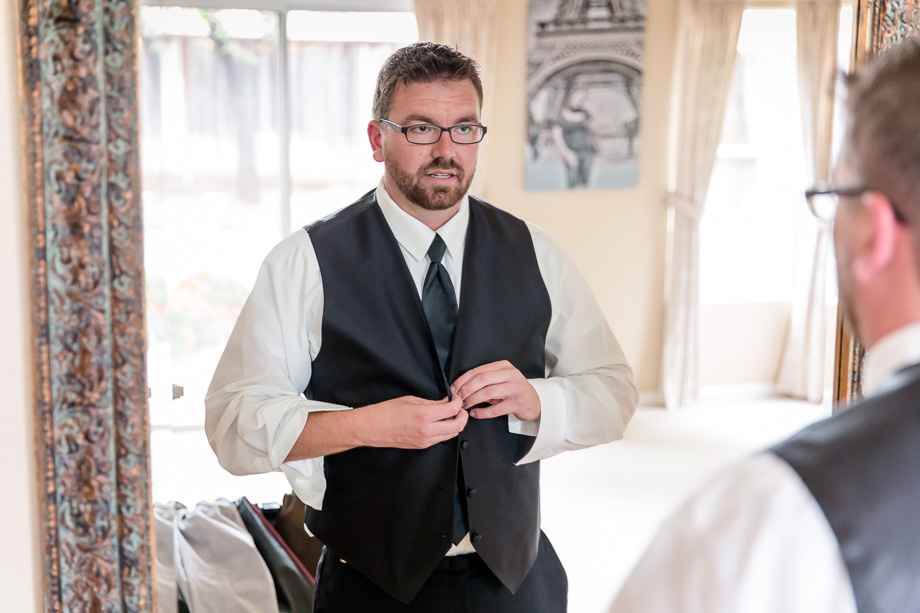 groom buttoning up his vest