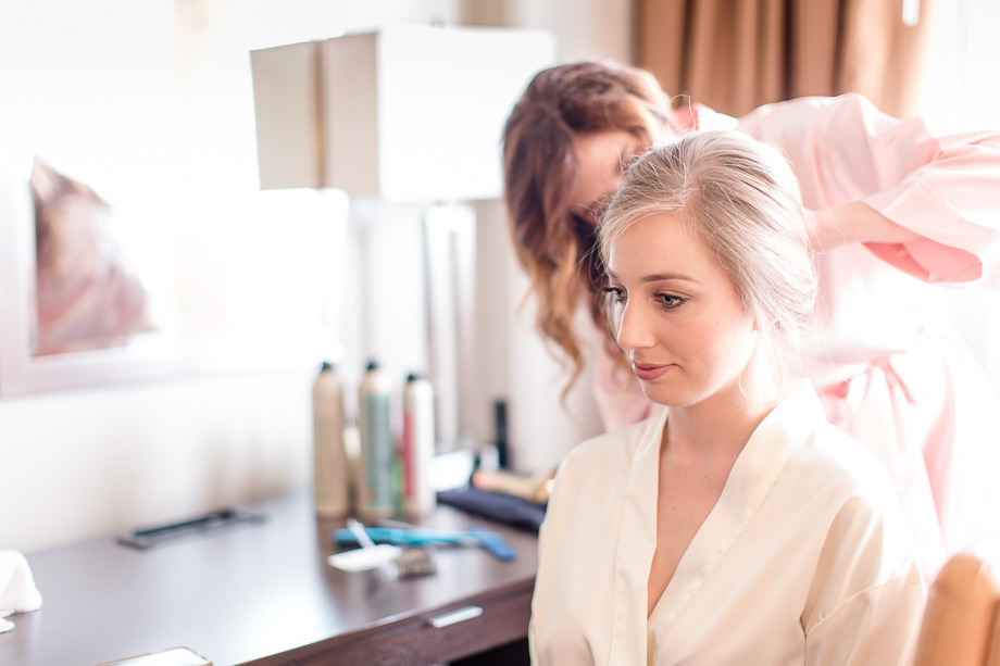 bride having her hair done by her best friend at the hotel room