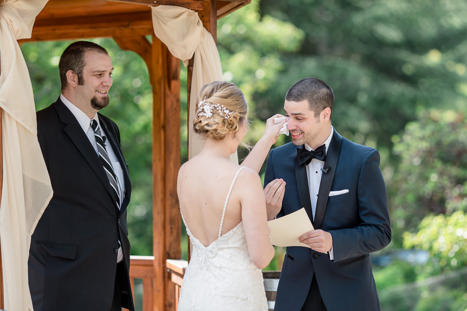 bride wiping tears for the groom during their vow exchange - candid wedding moments