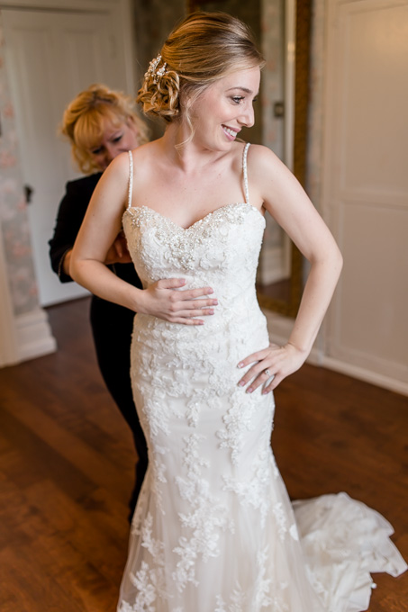 bride getting into her dress by the help of her mother