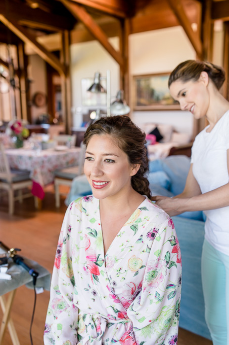bride in her floral bridal robe having her hair done