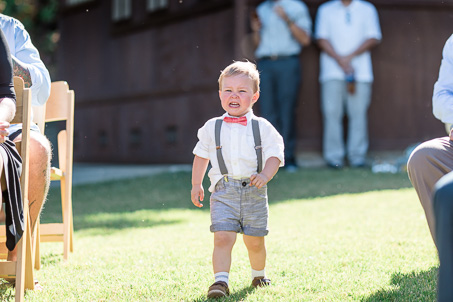 funny photo of the ring bearer running down the aisle crying