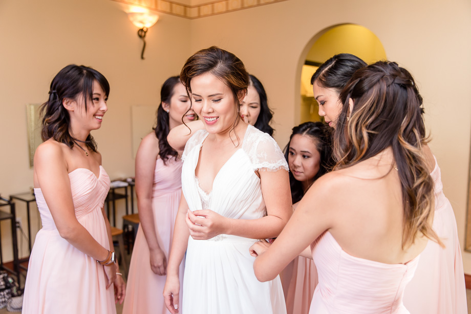 bridesmaids are all helping the bride to get into her wedding dress at the bridal suite