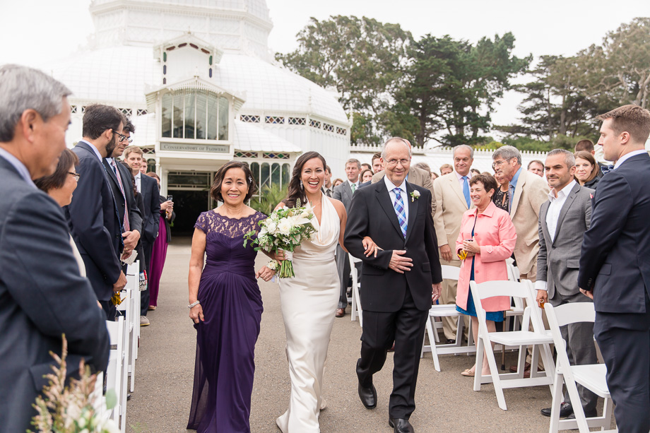 bride walking down the aisle escorted by parents