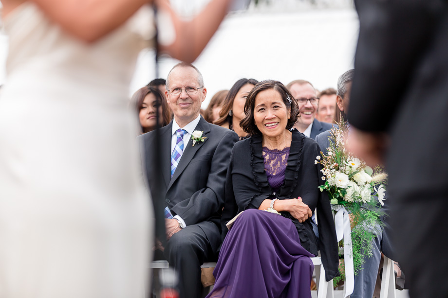 a candid photo of brides parents smiling at the newlyweds vows