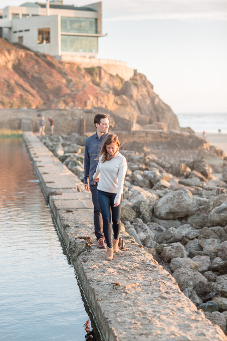 engaged couple walking along the shore