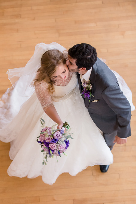 a candid photo from the balcony of the couple walking down the aisle and kissing
