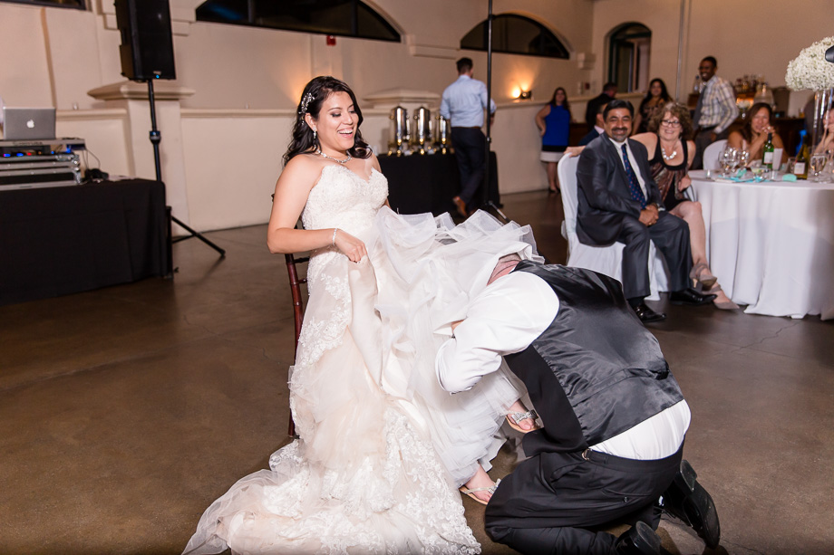 groom getting the garter belt off the brides leg