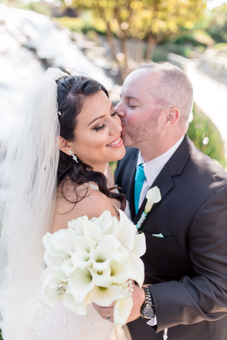 a sweet moment between bride and groom in front of the bridges golf club waterfall