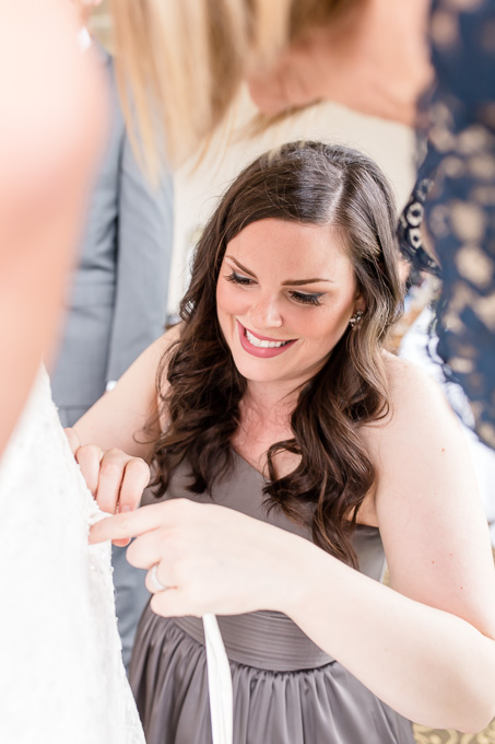 bridesmaid zipping up the dress for the bride