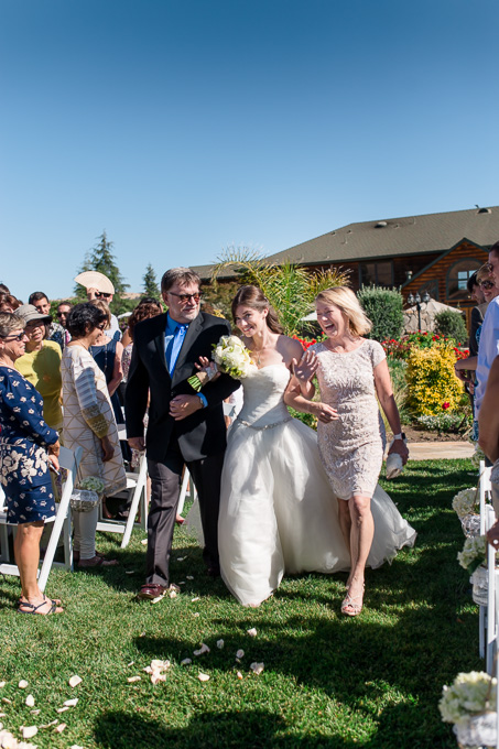bride walking down the aisle escorted by happy parents